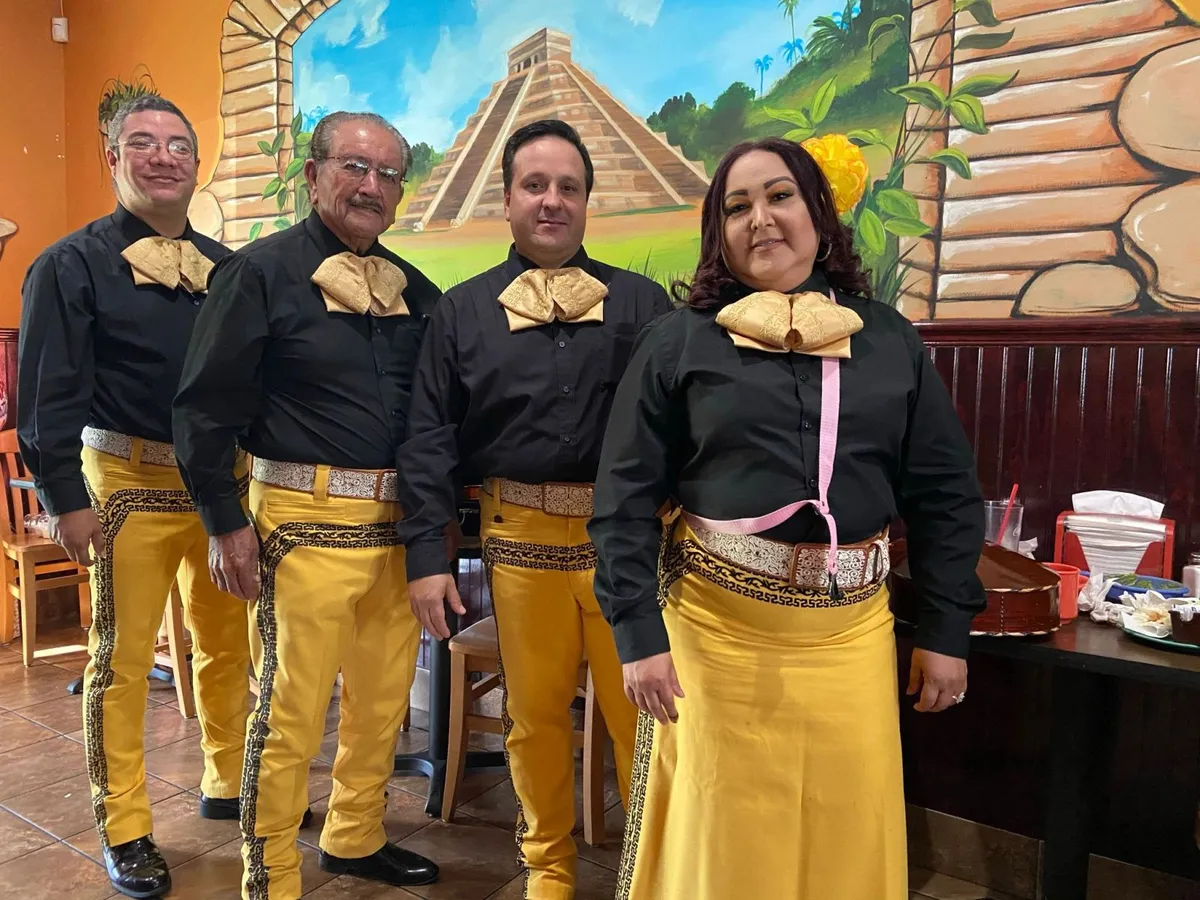 Mariachi con trajes negros y dorados en un restaurante